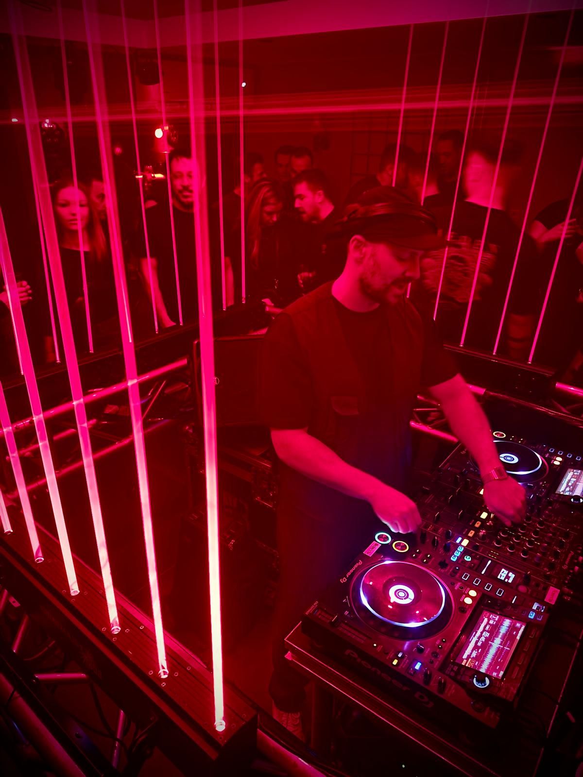 Een DJ achter de draaitafels met lasers boven de dansvloer